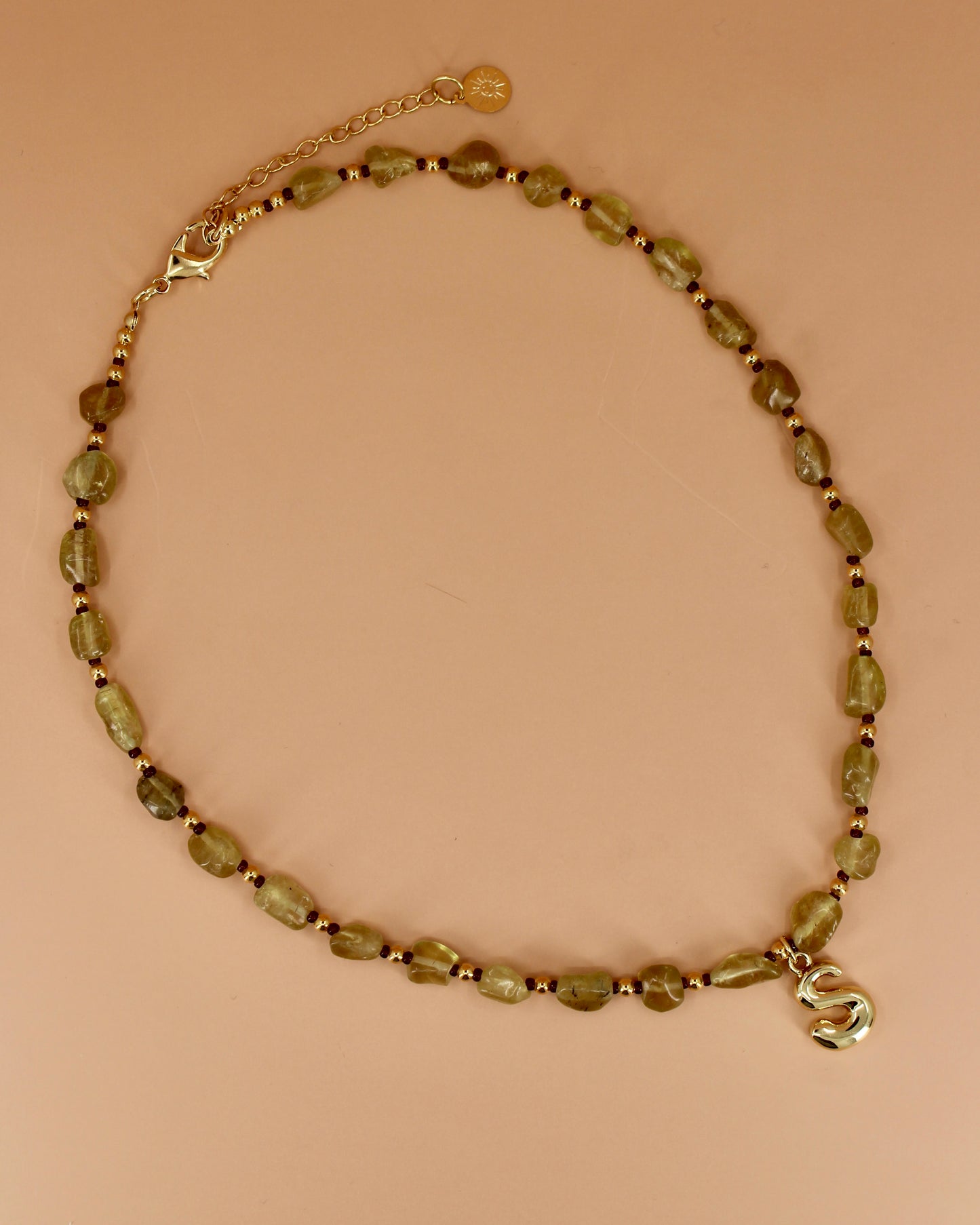 Necklace with green beads and a gold clasp on a beige background