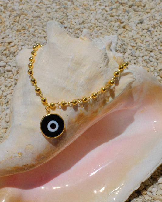 Gold beaded necklace with a black eye pendant inside a shell gold plated