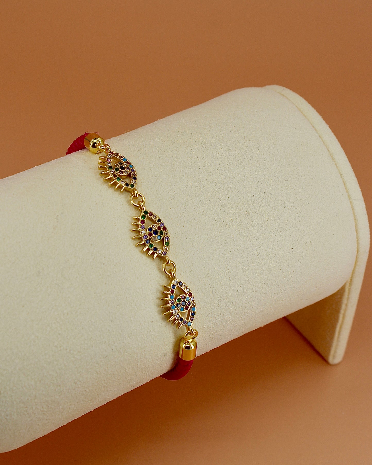Adjustable cord bracelet with three gold and enamel evil eye charms, handmade coastal jewelry by Cuya, available in multiple colors.