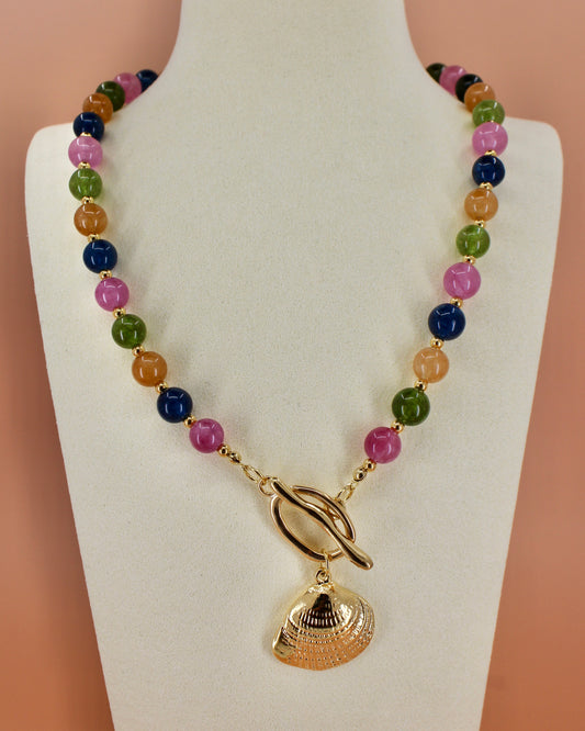 Multicolored beaded bracelet with a gold shell charm on a beige background