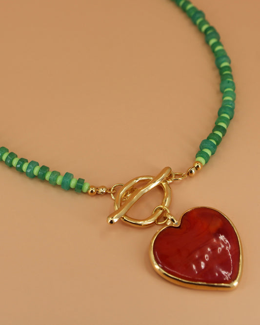 Handmade green beaded necklace with red heart pendant and gold toggle clasp, colorful coastal statement jewelry by Cuya.