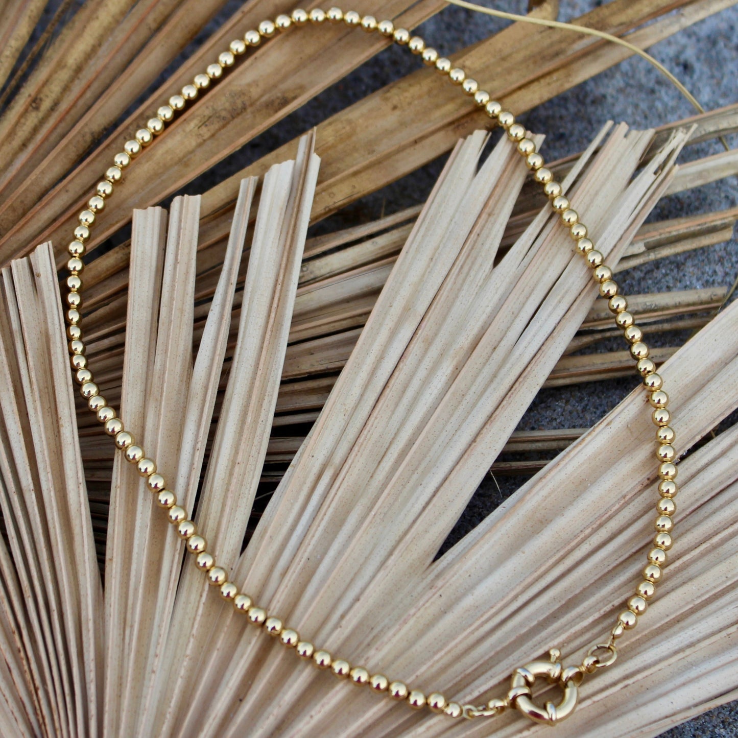 Elegant in its simplicity, the Cove Necklace features a seamless strand of polished gold beads, secured with a timeless circular sailor clasp. Understated yet radiant, it’s the kind of essential that elevates every outfit — from casual daywear to evening chic. Let your style shine with this piece — timeless, refined, and effortlessly graceful.