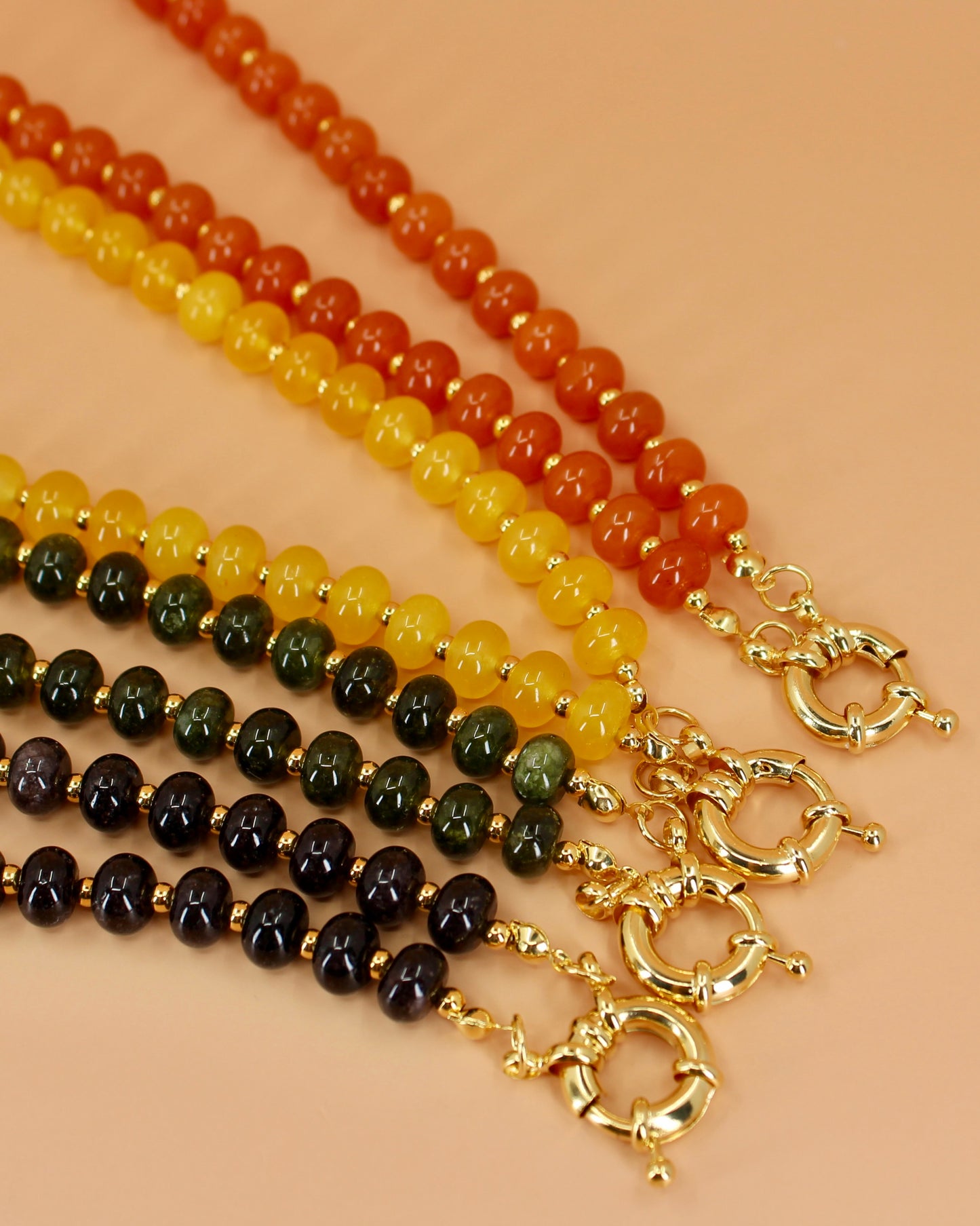 Handmade beaded necklaces in navy blue, green, yellow and orange with gold sailor clasps for interchangeable charms, customizable coastal jewelry by Cuya.