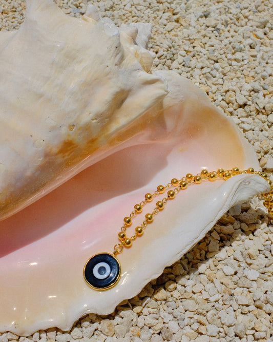 Gold beaded necklace with a black eye pendant inside a shell gold plated