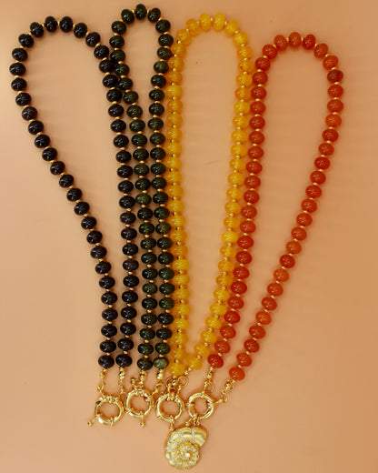 Handmade beaded necklaces in navy blue, green, yellow and orange with gold sailor clasps for interchangeable charms, customizable coastal jewelry by Cuya.