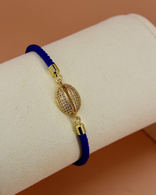 Adjustable cord bracelet with gold cowrie charm, handmade coastal jewelry by Cuya, available in multiple colors.