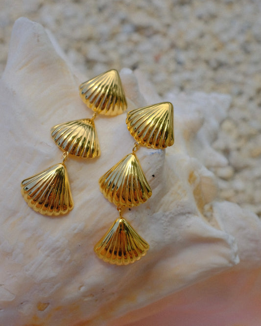Gold shell-shaped earrings on a seashell beachy summer beach ocean sea hippie boho chic travel trendy stylish style