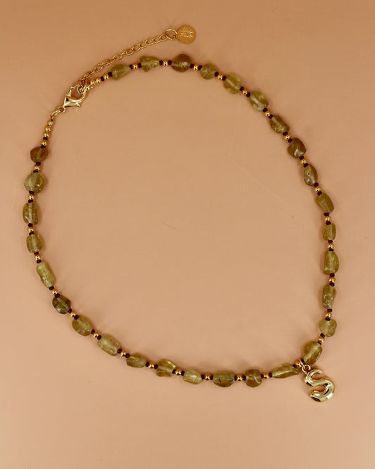 Necklace with green beads and a gold clasp on a beige background