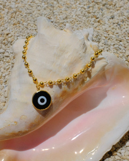 Gold beaded necklace with a black eye pendant inside a shell gold plated
