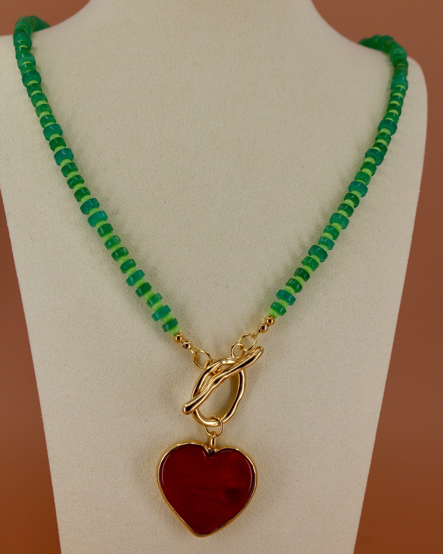 Handmade green beaded necklace with red heart pendant and gold toggle clasp, colorful coastal statement jewelry by Cuya.