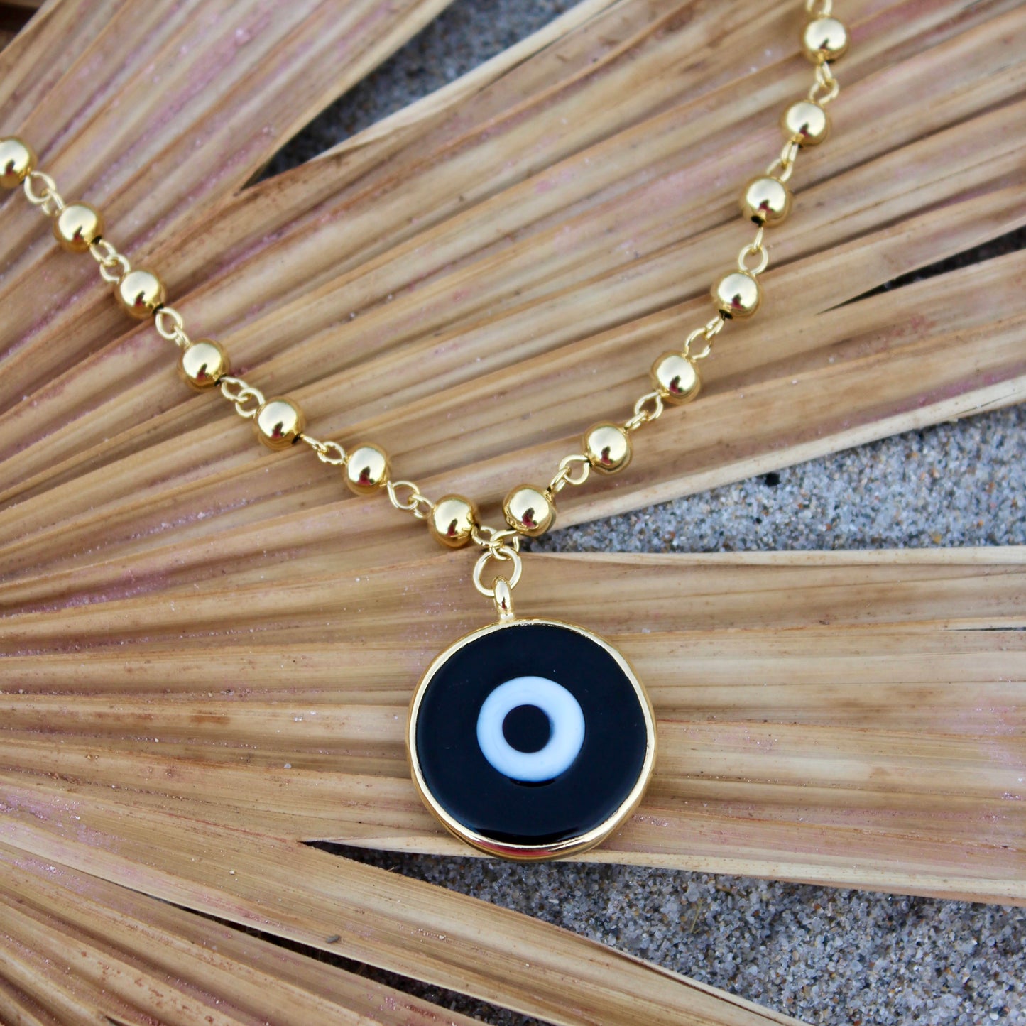 Gold beaded necklace with a black eye pendant inside a shell gold plated