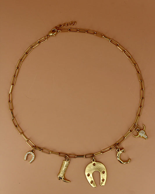 18k gold plated Western charm necklace with customizable initial, horseshoe, cowboy boot, bull skull, and paperclip chain, bold cowgirl jewelry by Cuya.