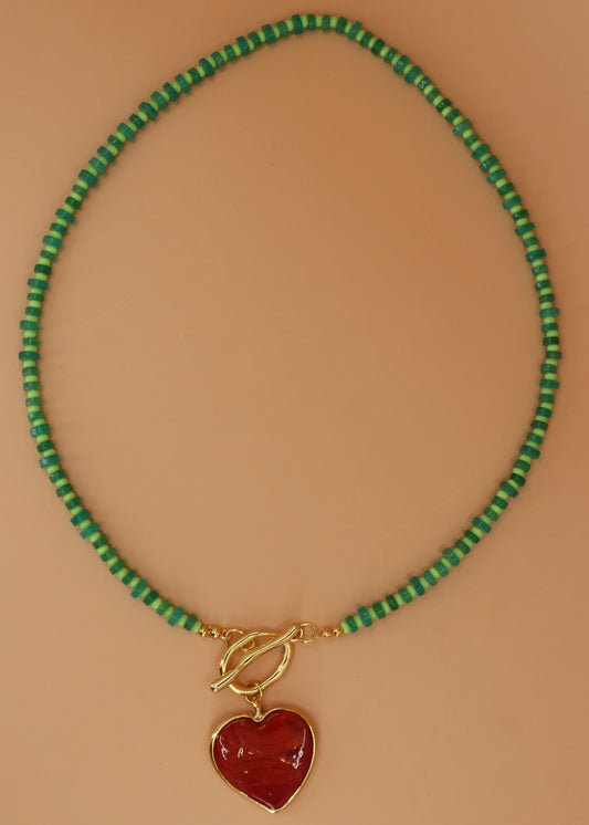 Handmade green beaded necklace with red heart pendant and gold toggle clasp, colorful coastal statement jewelry by Cuya.