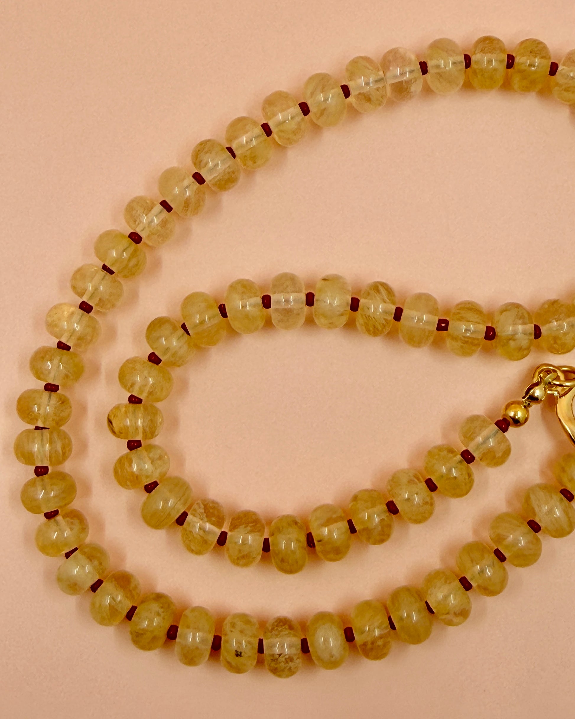 Handcrafted clear gemstone necklace with red accent beads and a gold plated toggle clasp. The IO Necklace is available in 17 inches.