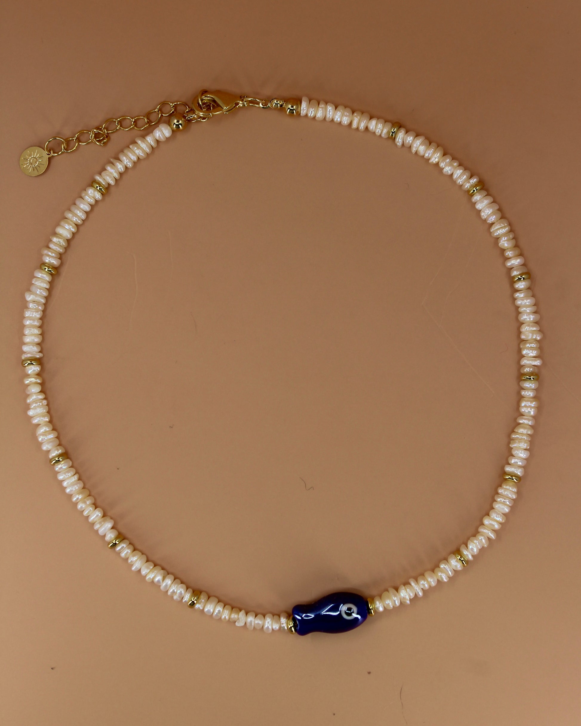 Handmade freshwater pearl necklace with gold accents and colorful glass fish charm, ocean-inspired coastal jewelry by Cuya.