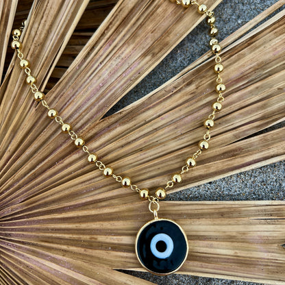 Gold beaded necklace with a black eye pendant inside a shell gold plated