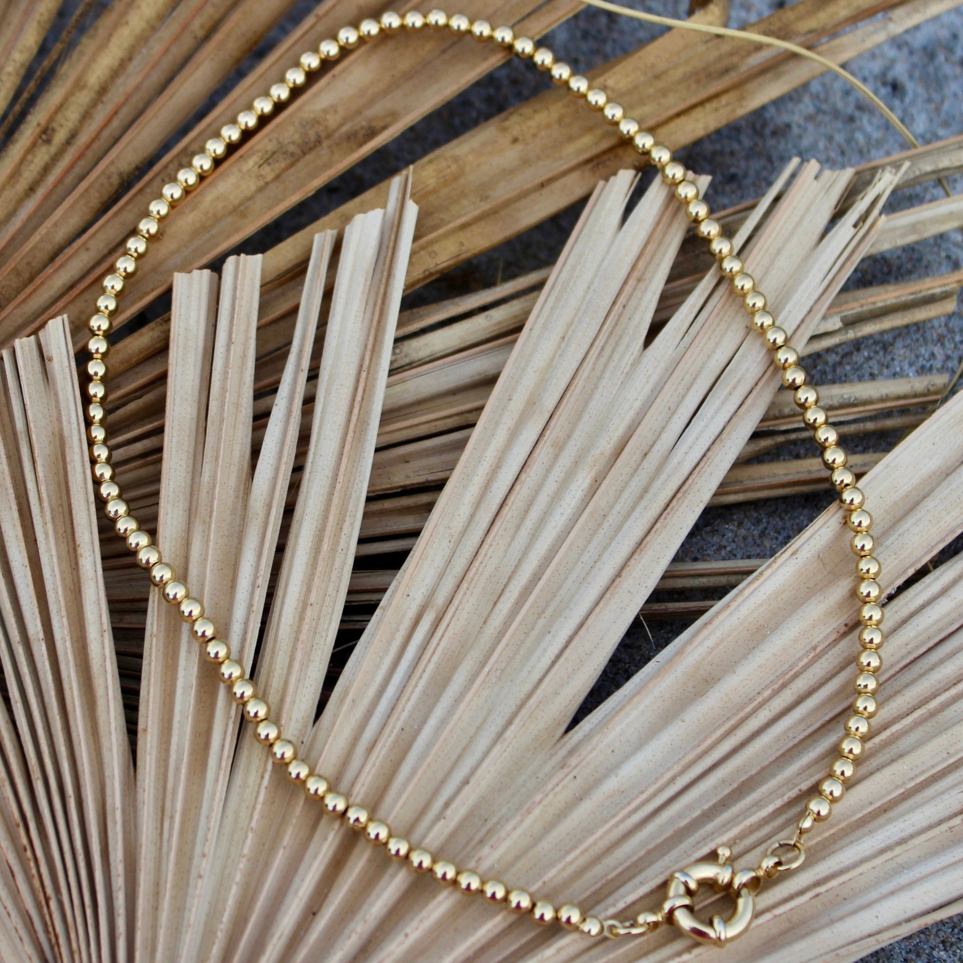Elegant in its simplicity, the Cove Necklace features a seamless strand of polished gold&nbsp; beads, secured with a timeless circular sailor clasp. Understated yet radiant, it’s the kind of essential that elevates every outfit — from casual daywear to evening chic. Let your style shine with this piece — timeless, refined, and effortlessly graceful.