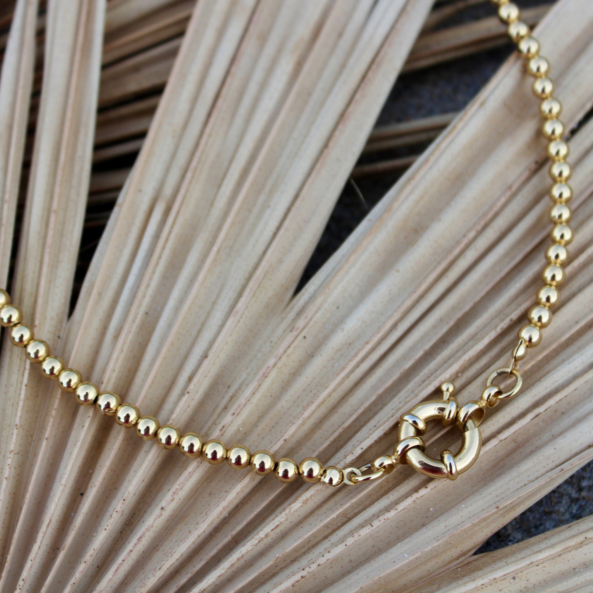 Elegant in its simplicity, the Cove Necklace features a seamless strand of polished gold&nbsp; beads, secured with a timeless circular sailor clasp. Understated yet radiant, it’s the kind of essential that elevates every outfit — from casual daywear to evening chic. Let your style shine with this piece — timeless, refined, and effortlessly graceful.