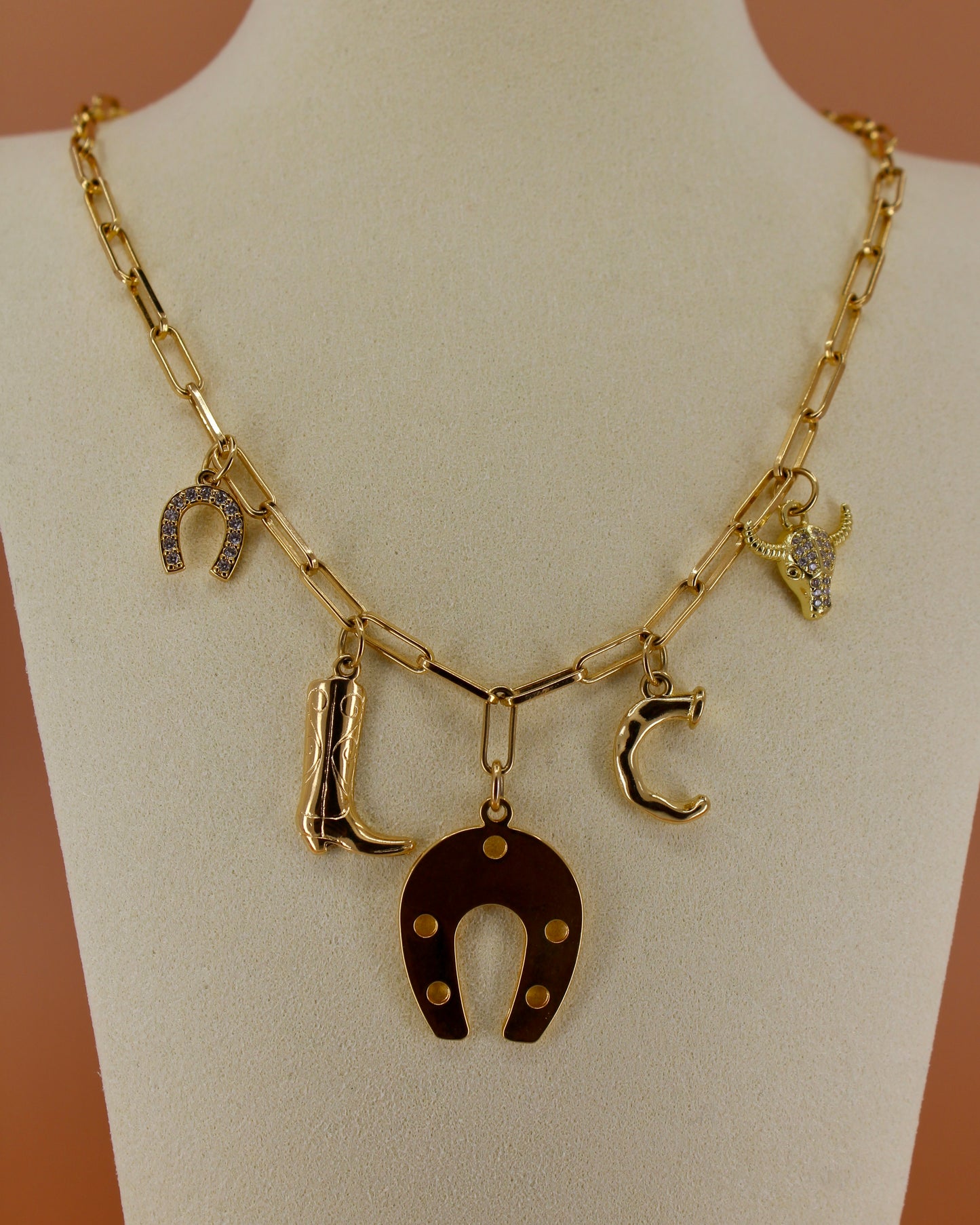 18k gold plated Western charm necklace with customizable initial, horseshoe, cowboy boot, bull skull, and paperclip chain, bold cowgirl jewelry by Cuya.