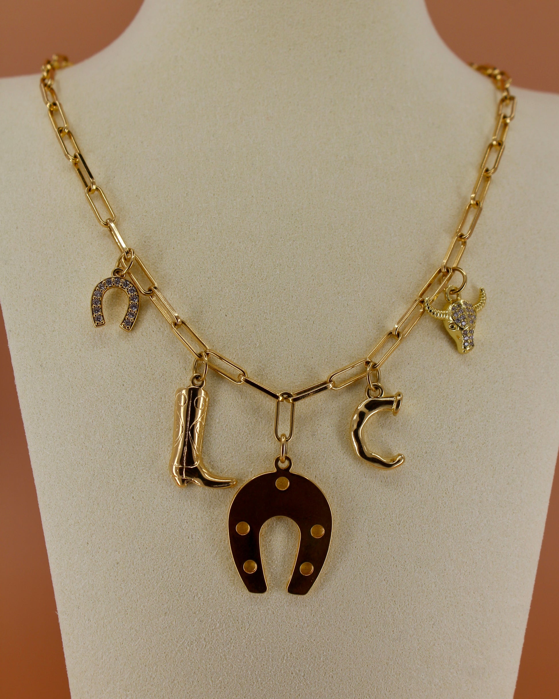 18k gold plated Western charm necklace with customizable initial, horseshoe, cowboy boot, bull skull, and paperclip chain, bold cowgirl jewelry by Cuya.