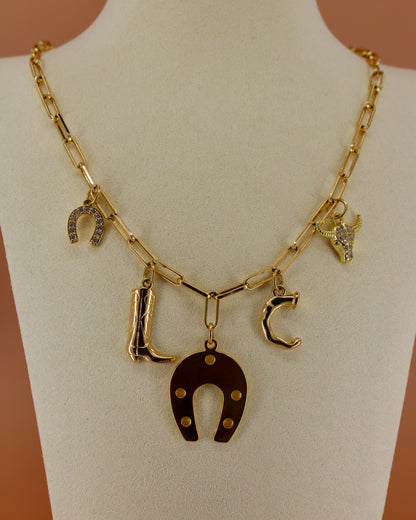 18k gold plated Western charm necklace with customizable initial, horseshoe, cowboy boot, bull skull, and paperclip chain, bold cowgirl jewelry by Cuya.