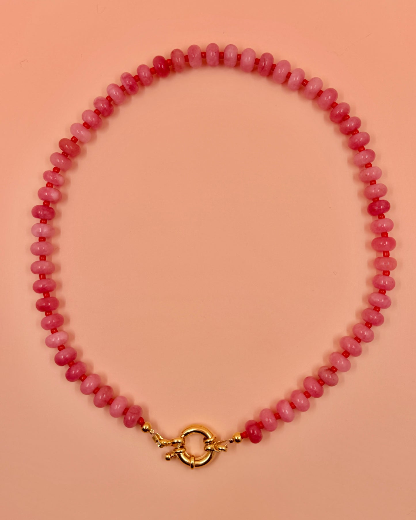 Handmade beaded necklaces in pink with gold sailor clasps for interchangeable charms, customizable coastal jewelry by Cuya.