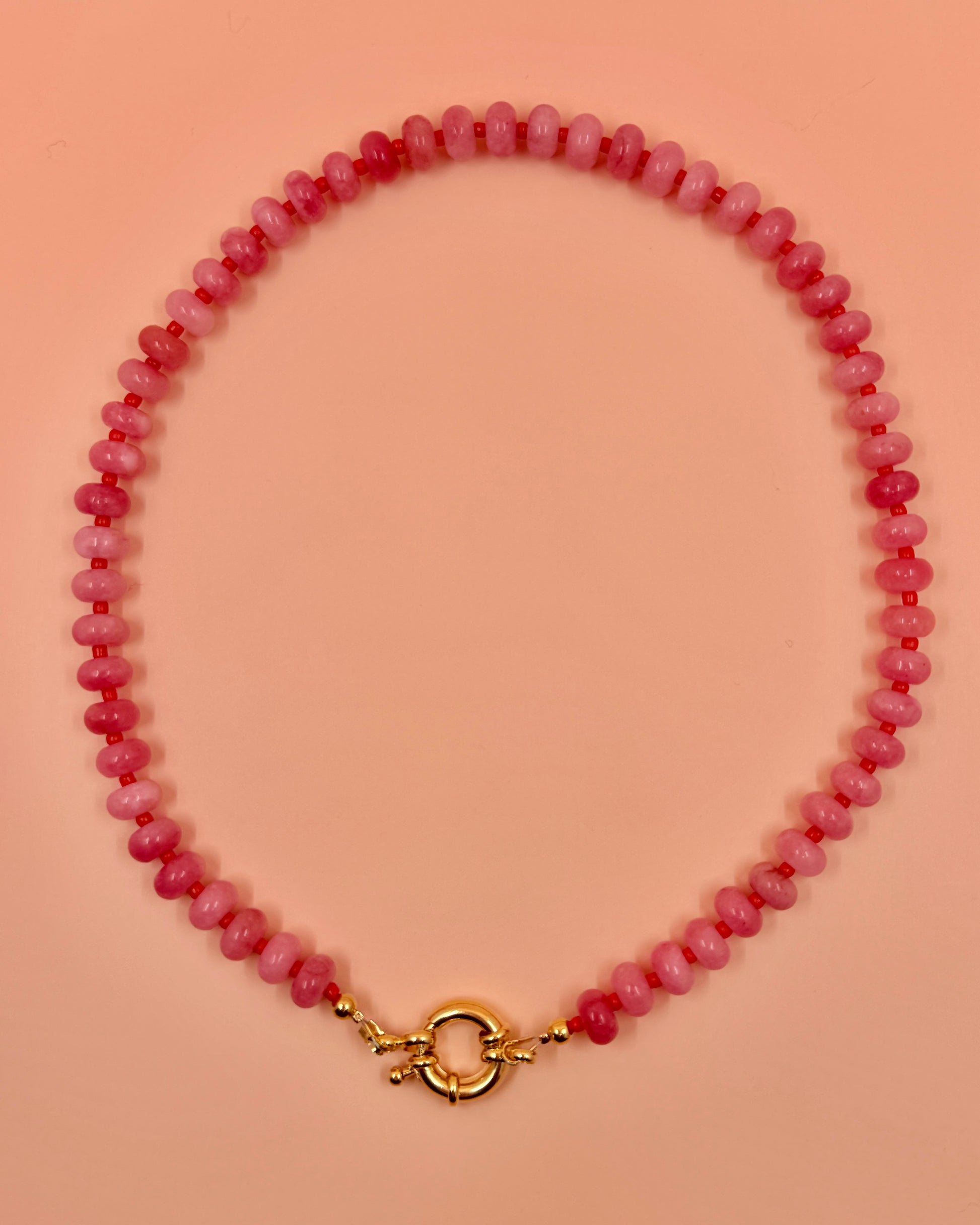 Handmade beaded necklaces in pink with gold sailor clasps for interchangeable charms, customizable coastal jewelry by Cuya.