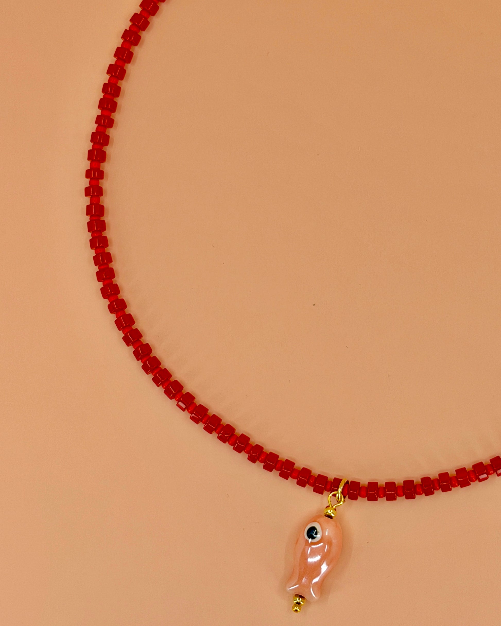 Handcrafted red gemstone necklace with a pink ceramic fish pendant. The Riva Necklace is available in 16”, 18”, and 20” lengths.