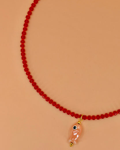 Handcrafted red gemstone necklace with a pink ceramic fish pendant. The Riva Necklace is available in 16”, 18”, and 20” lengths.