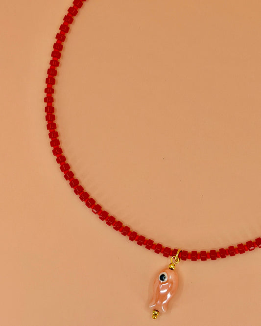 Handcrafted red gemstone necklace with a pink ceramic fish pendant. The Riva Necklace is available in 16”, 18”, and 20” lengths.