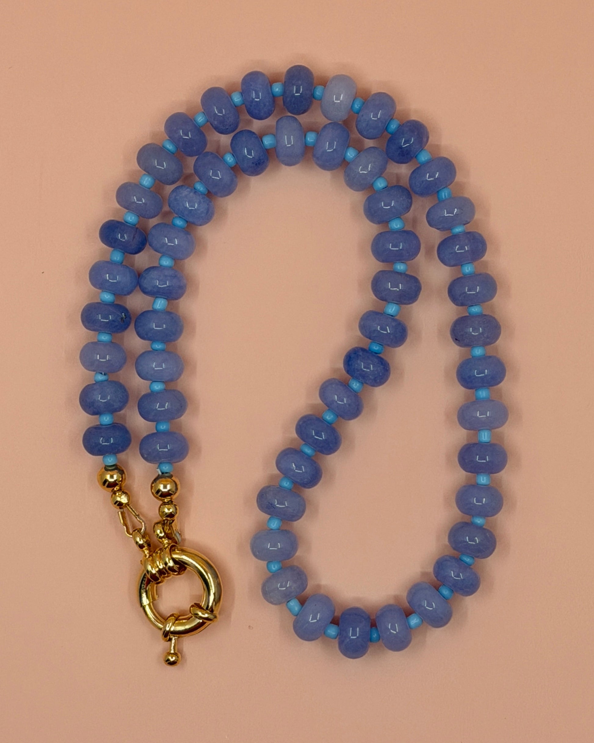 Blue beaded necklace with a gold clasp on a beige background