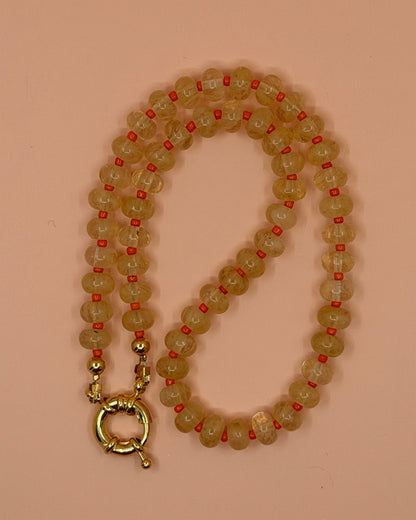 Beaded necklace with a gold clasp on a pink background