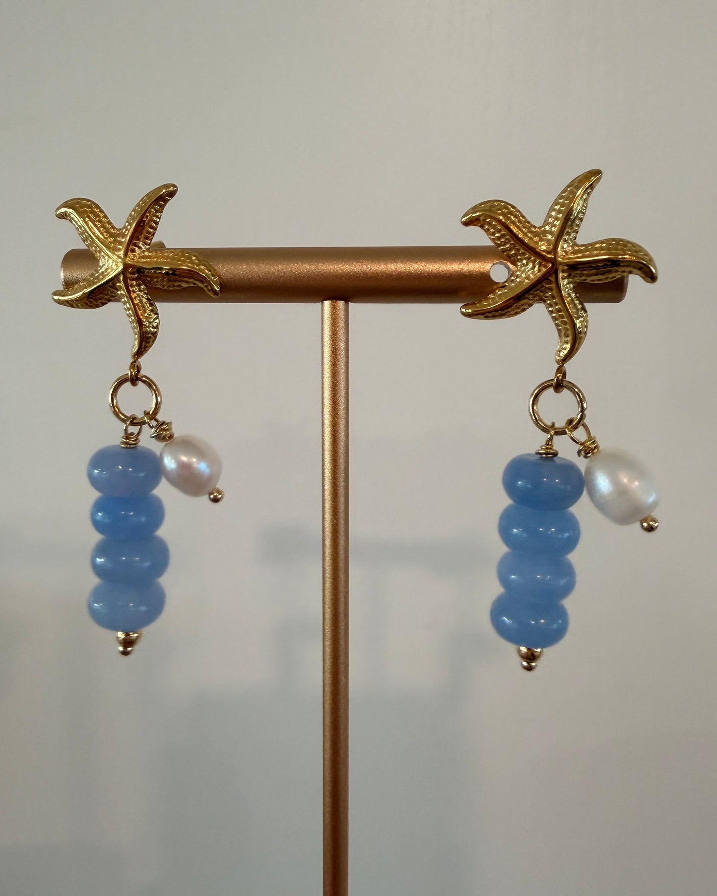 Limited-edition starfish earrings featuring gold-plated stainless steel, jade beads, and freshwater pearls. Handmade in small batches by Cuya Jewelry.