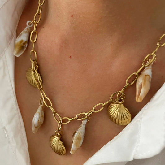 Gold necklace with shell charms worn by a person